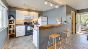 Una cocina moderna con armarios blancos, una isla de madera con taburetes y vistas al exterior.