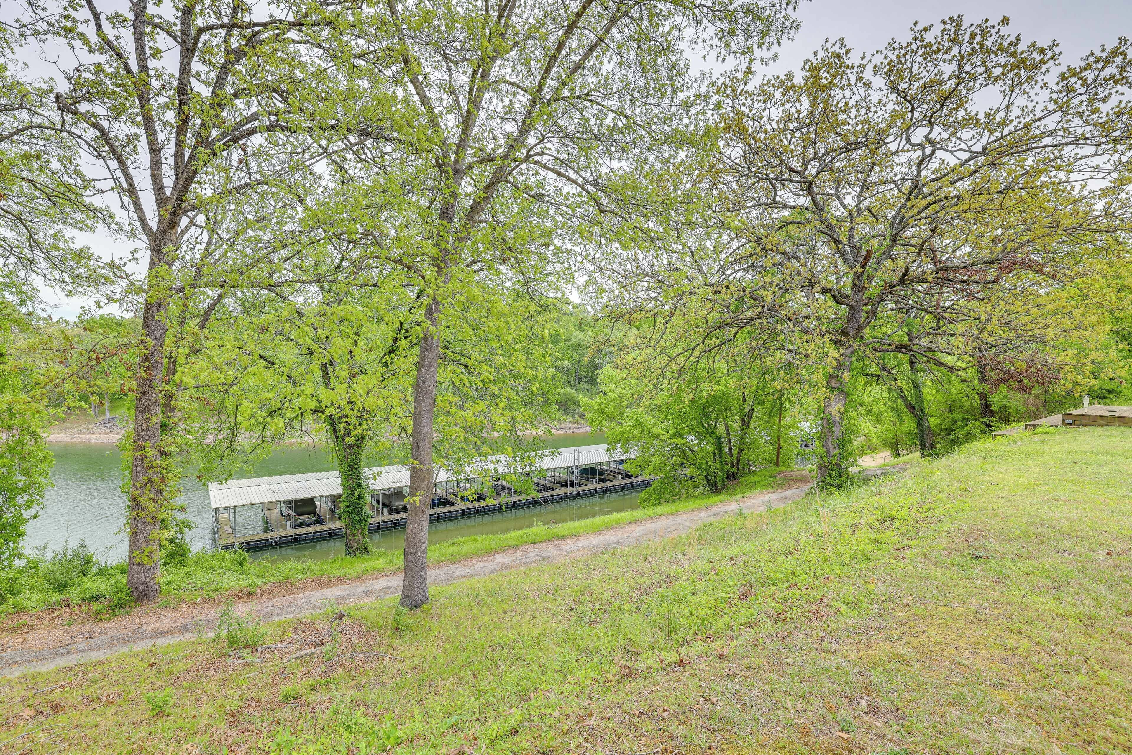 A riverside area with a dock and a small building, surrounded by trees and grassy banks.