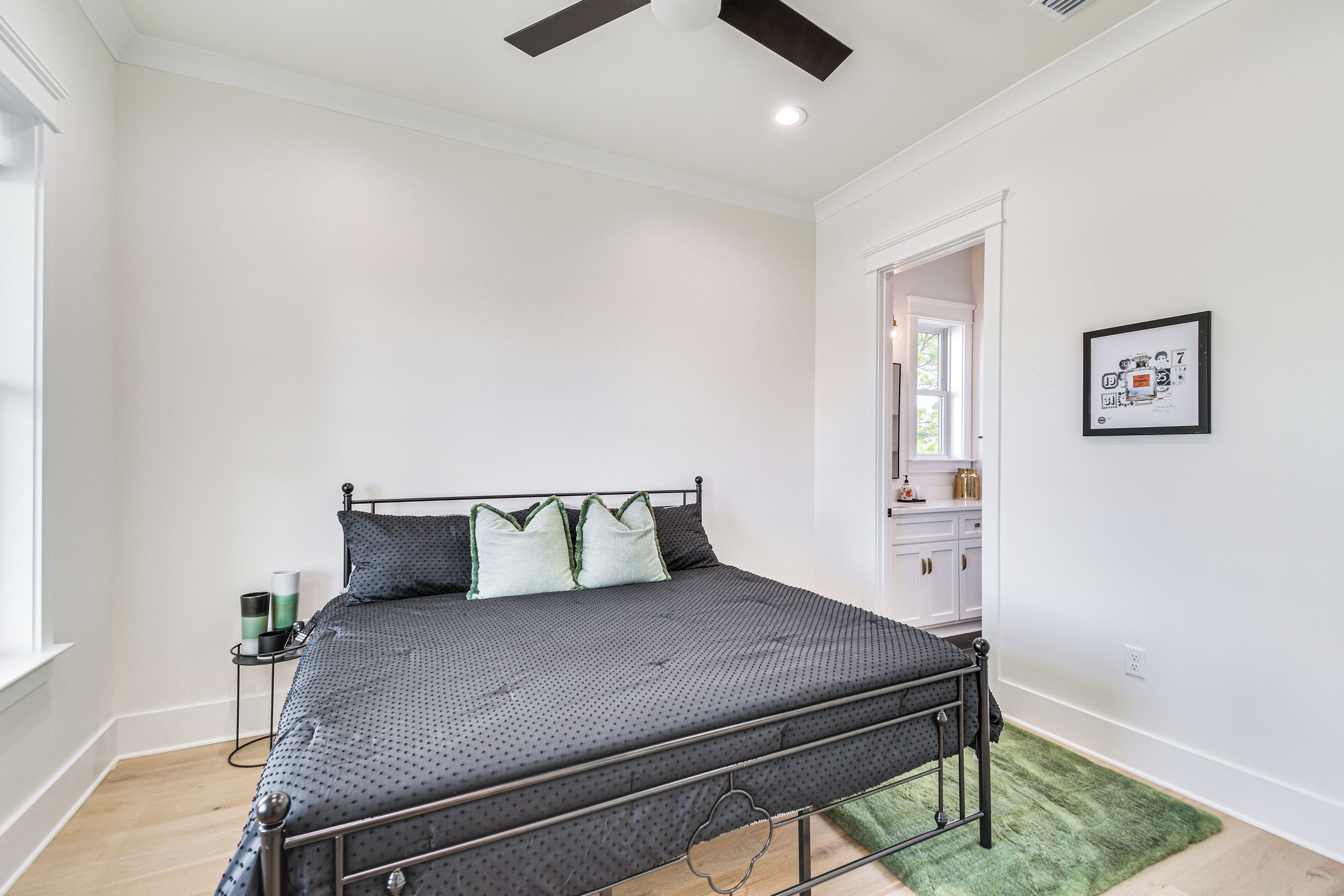 A bedroom with a bed, a nightstand, a green rug, and a framed picture on the wall.