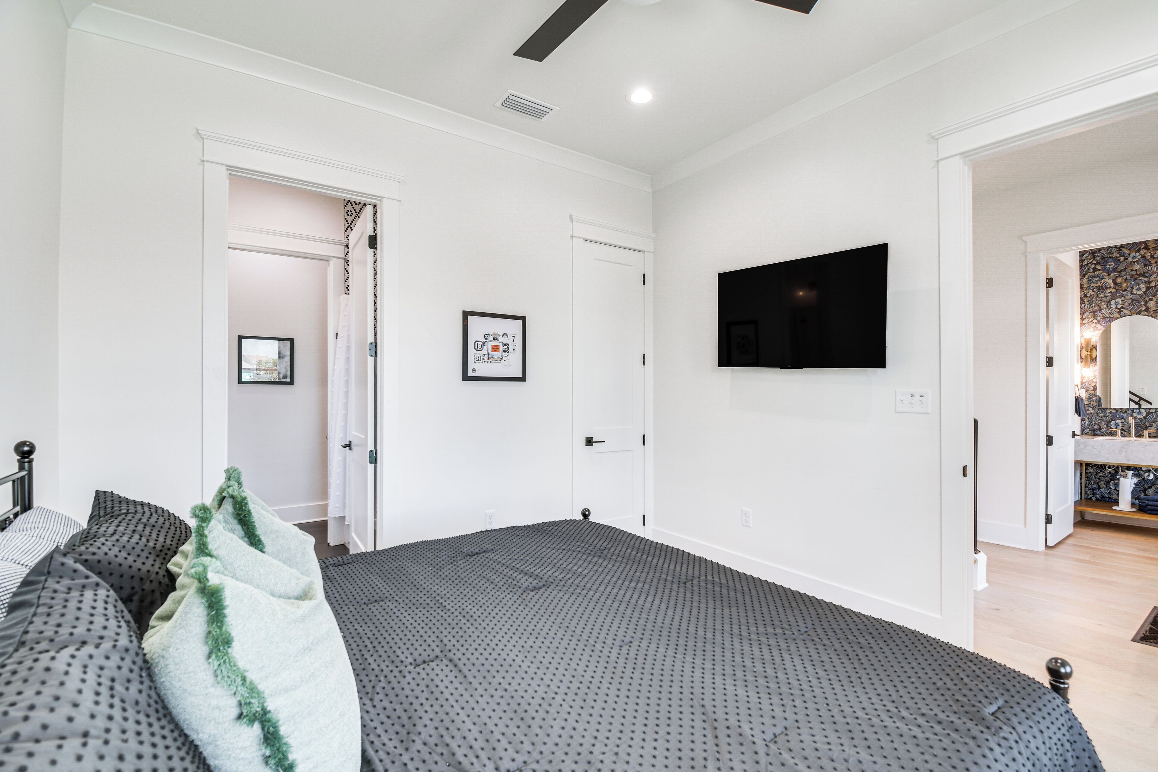 Un dormitorio con una cama grande, un televisor montado en la pared y una puerta que da a otra habitación.