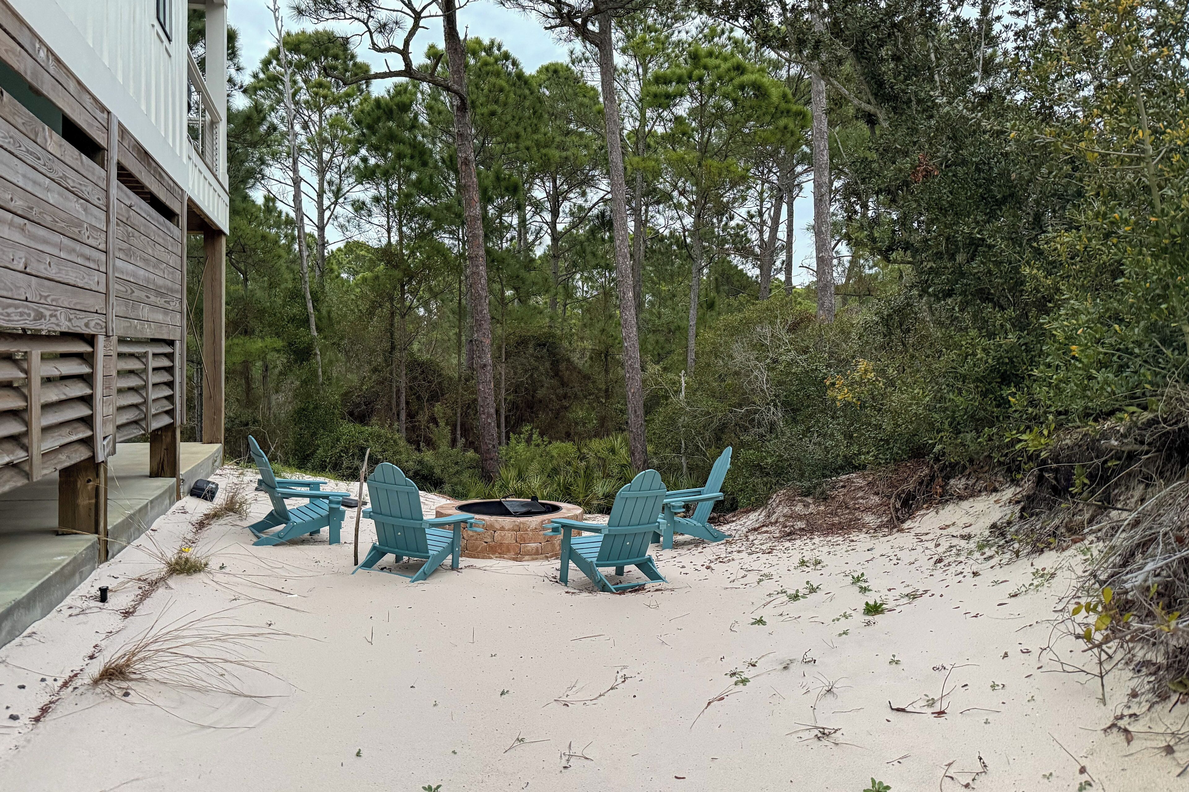 Une terrasse au bord de la plage, avec quatre fauteuils Adirondack verts et un foyer.