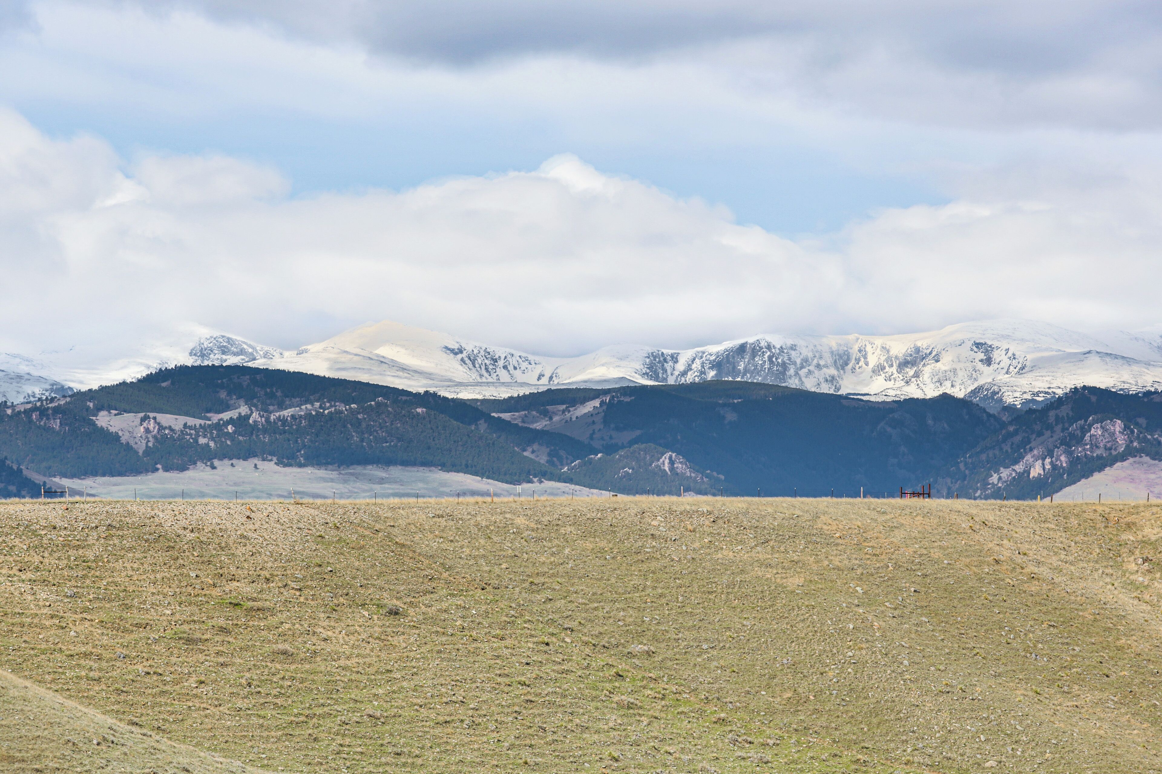 A mountainous landscape with a clear sky and snow-capped peaks in the background.