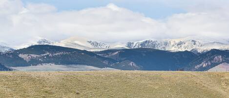 A mountainous landscape with a clear sky and snow-capped peaks in the background.