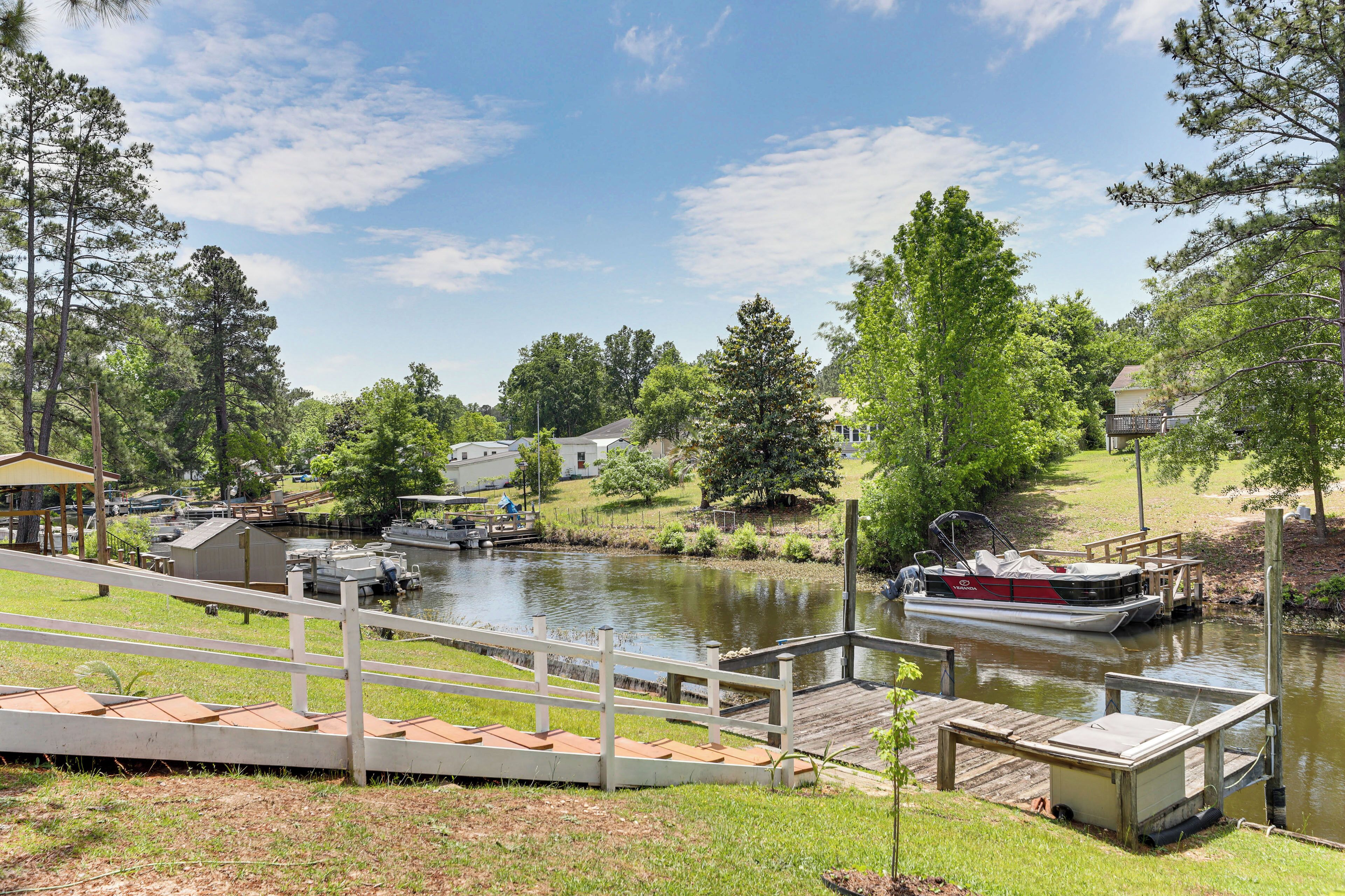 A riverside dock with a boat, a wooden walkway, and a small building.