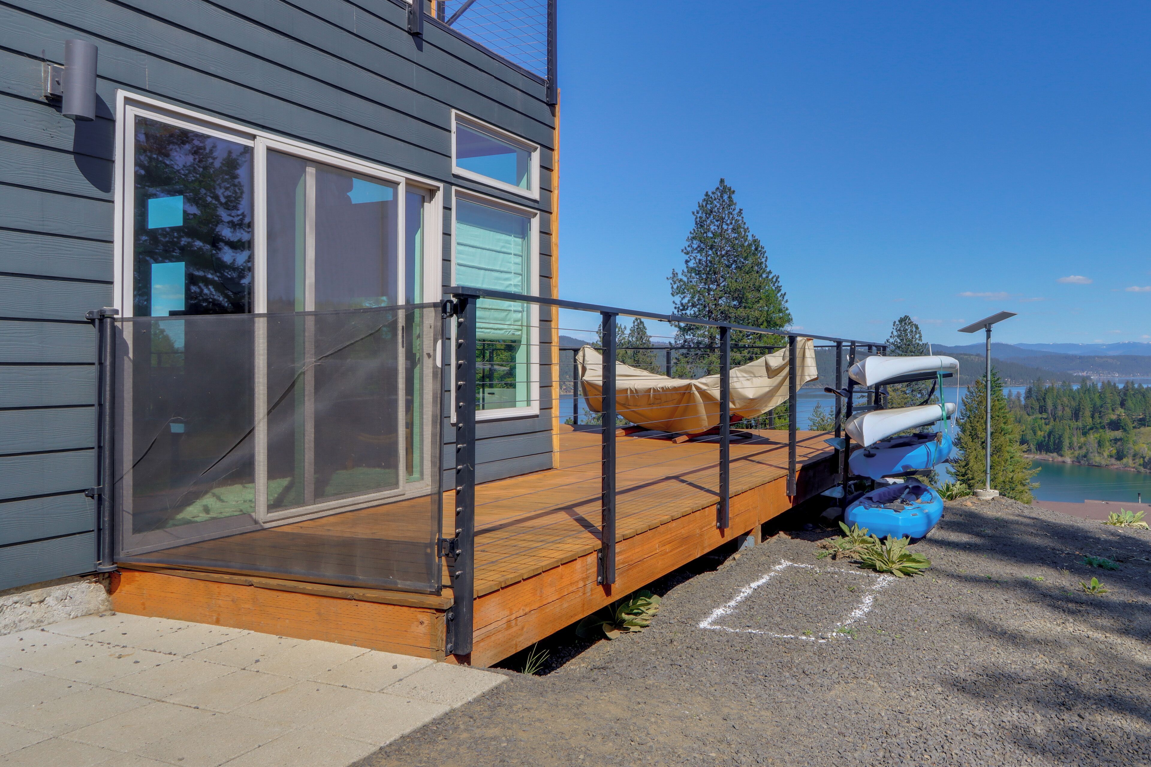 Una casa moderna con terraza, un kayak y una canoa junto a un lago.