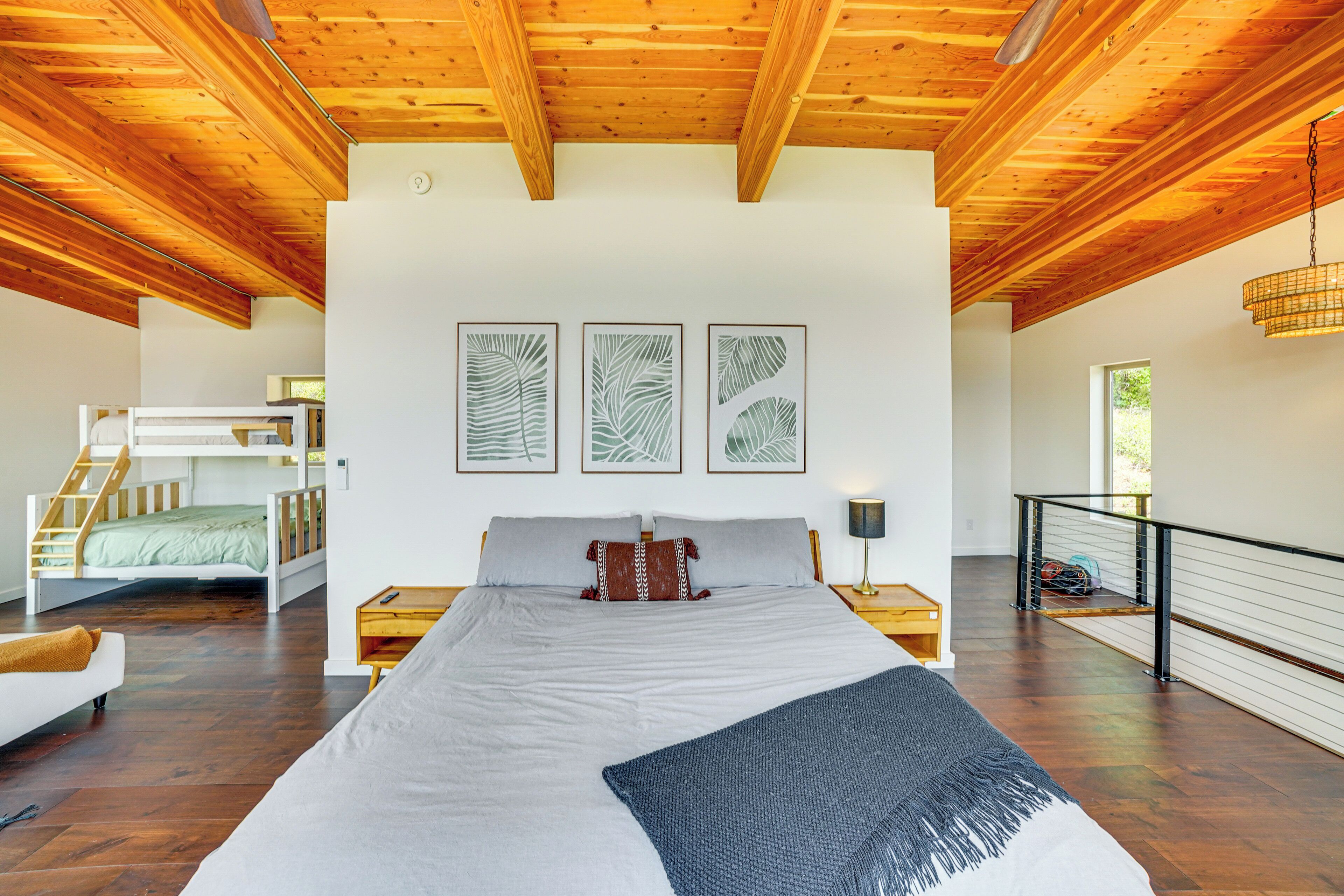 Un'ampia camera da letto con un grande letto, travi in legno a soffitto e quadri appesi al muro, oltre a un letto a castello.