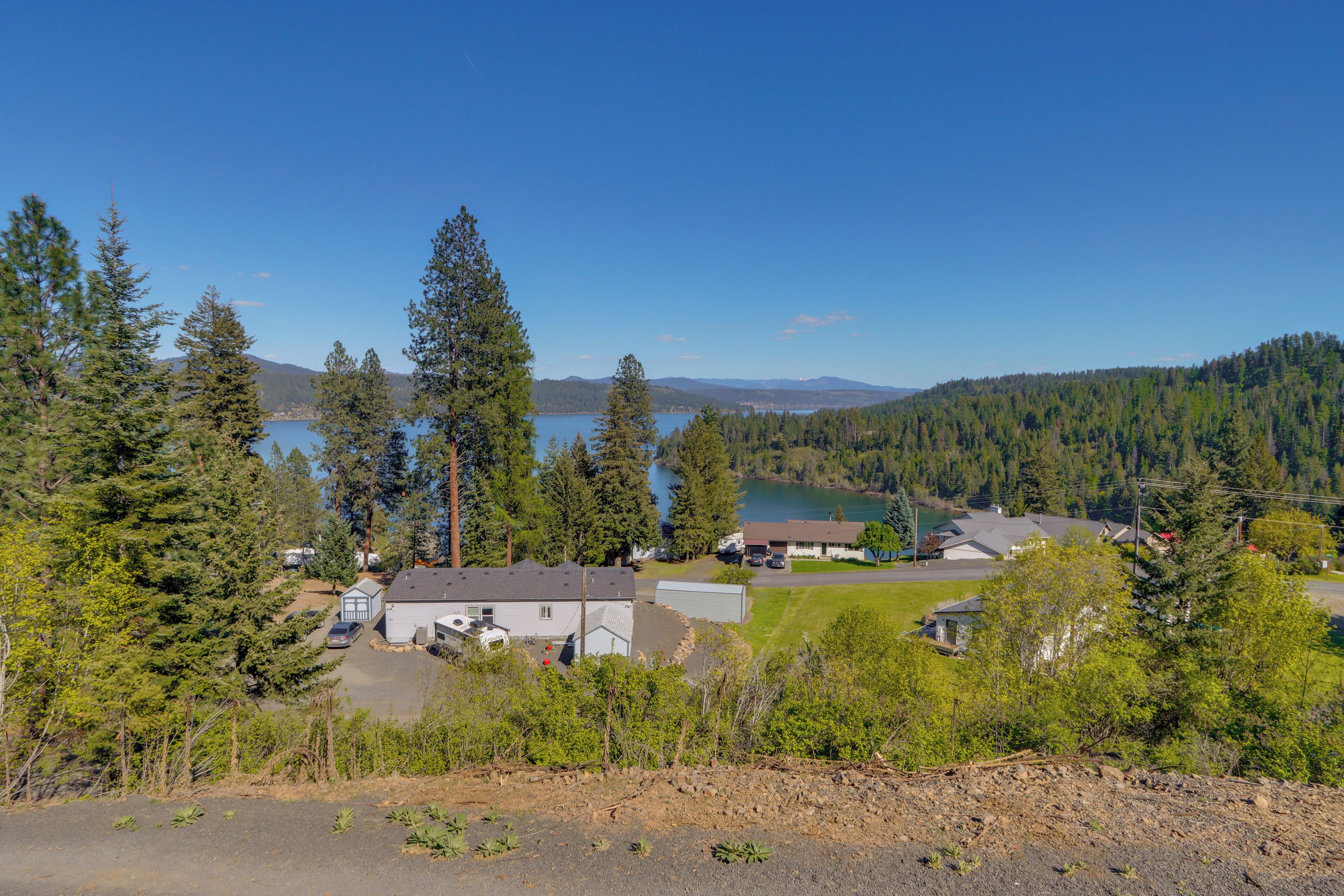 A residential area with houses, a lake, and a forested hill in the background.