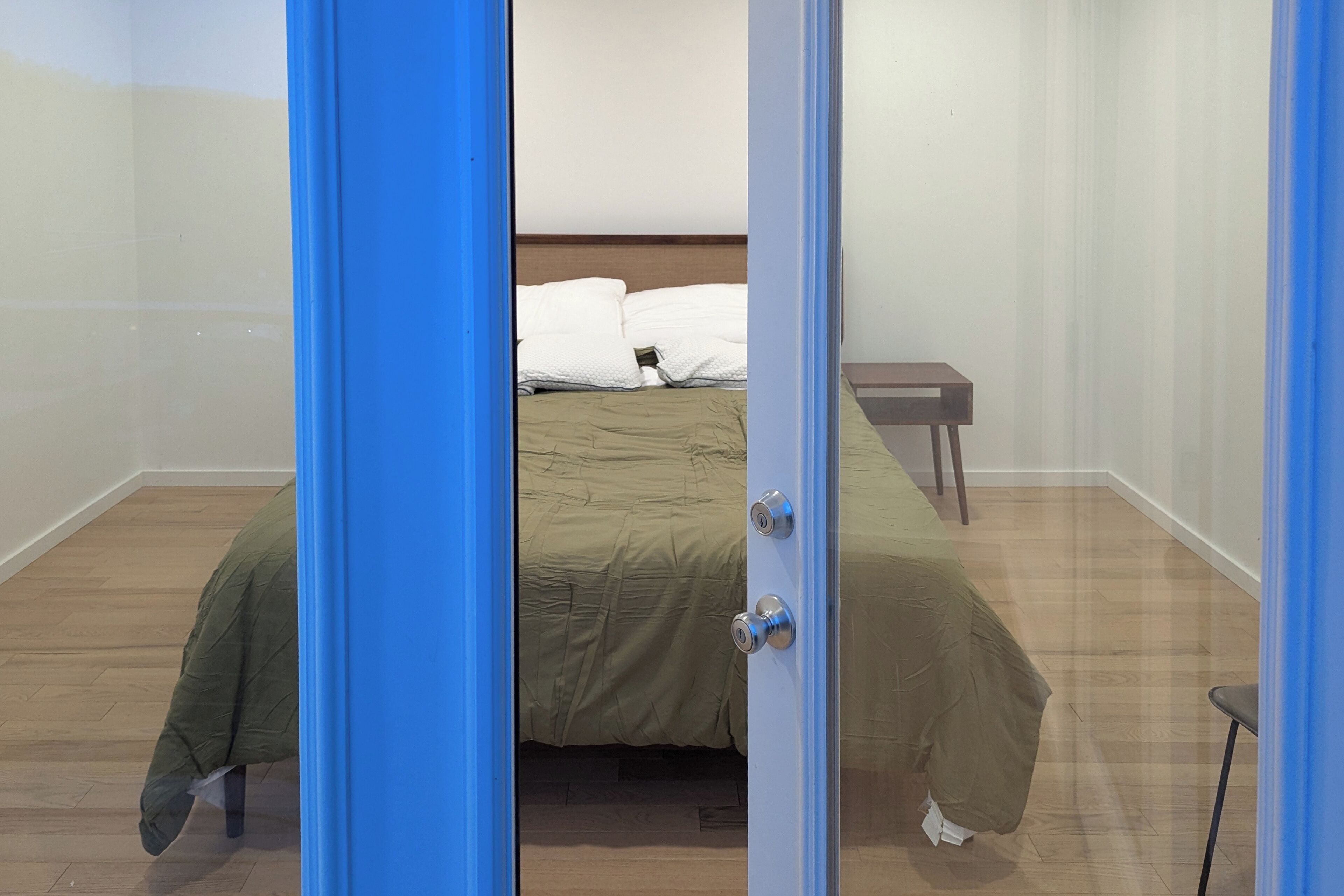 Une pièce avec un lit, une petite table et une porte.