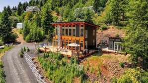 A modern house with a deck, surrounded by dense forest. - Mid-century Escape: Lake Views, Steps to Cave Bay! (Worley)