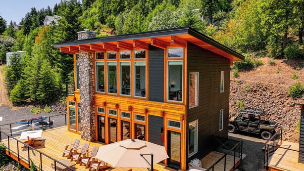 A modern cabin with a deck, large windows, and a stone pillar. - Mid-century Escape: Lake Views, Steps to Cave Bay! (Worley)