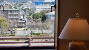 Ein Zimmer mit Blick auf eine Stadtlandschaft und Berge durch ein Fenster.