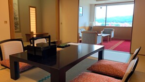 Ein Hotelzimmer mit Esstisch, Stühlen, Blick auf die Stadt und einer traditionellen japanischen Schiebetür.