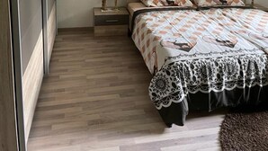 Une chambre à coucher avec un lit, des tables de chevet, un tableau et un plancher en bois.