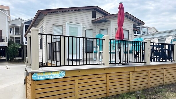 A residential building with a fenced patio area, a red umbrella, and a sign indicating a rental property. - 1050 Ocean Lakes Pet Friendly Golf Cart⛱️🏝️🩱🌊👙☀️🐚 (Myrtle Beach)
