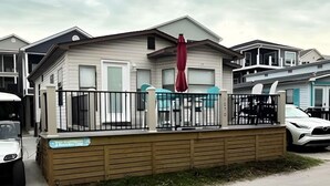 A single-story house with a fenced front yard, a red umbrella, and a white car parked in front. - 1050 Ocean Lakes Pet Friendly Golf Cart⛱️🏝️🩱🌊👙☀️🐚 (Myrtle Beach)