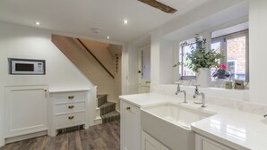 Une cuisine moderne avec des meubles blancs, un four à micro-ondes encastré et un grand évier.