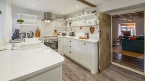 Une cuisine moderne avec des meubles blancs, un four encastré et un plafond avec une poutre en bois.