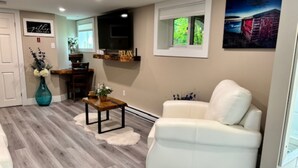 Un salon moderne avec un canapé blanc, un parquet en bois, une petite table basse et un tableau accroché au mur.
