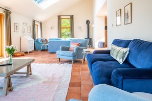 A spacious living room with a high ceiling, a fireplace, and a large window. - Mill Hill, Tittleshall, Norfolk (Wells-next-the-Sea)