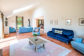 A spacious living area with a high ceiling, a fireplace, and a dining area visible through an open door. - Mill Hill, Tittleshall, Norfolk (Wells-next-the-Sea)