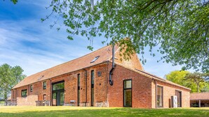 Un bâtiment en briques doté de grandes fenêtres et d’un espace extérieur abrité.