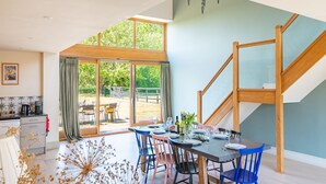 Un coin repas avec une table dressée pour quatre personnes, un escalier et une vue sur l’extérieur.