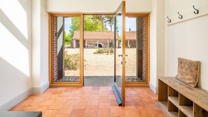 Une pièce dotée d’une porte-fenêtre coulissante donnant sur un espace extérieur, d’un banc et d’un porte-manteau fixé au mur.