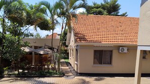 Un patio empedrado con un edificio de techo a la manera española, palmeras y mobiliario exterior.