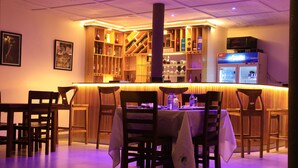 Un restaurante con zona de bar, muebles de madera y suelo de baldosas.