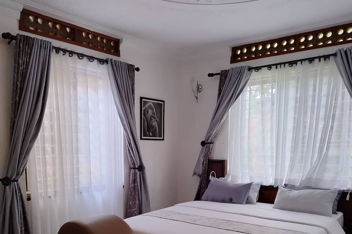 Une chambre à coucher avec un grand lit, un canapé marron et un plafond orné de motifs décoratifs.