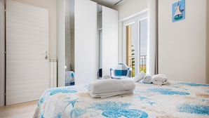 Una camera d'albergo con un letto, una sedia e vista sul balcone esterno.