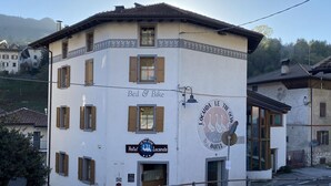A white building with brown shutters, a sign reading "Bed & Bike", and a logo for "Locanda Le Tre Oche Hotel".