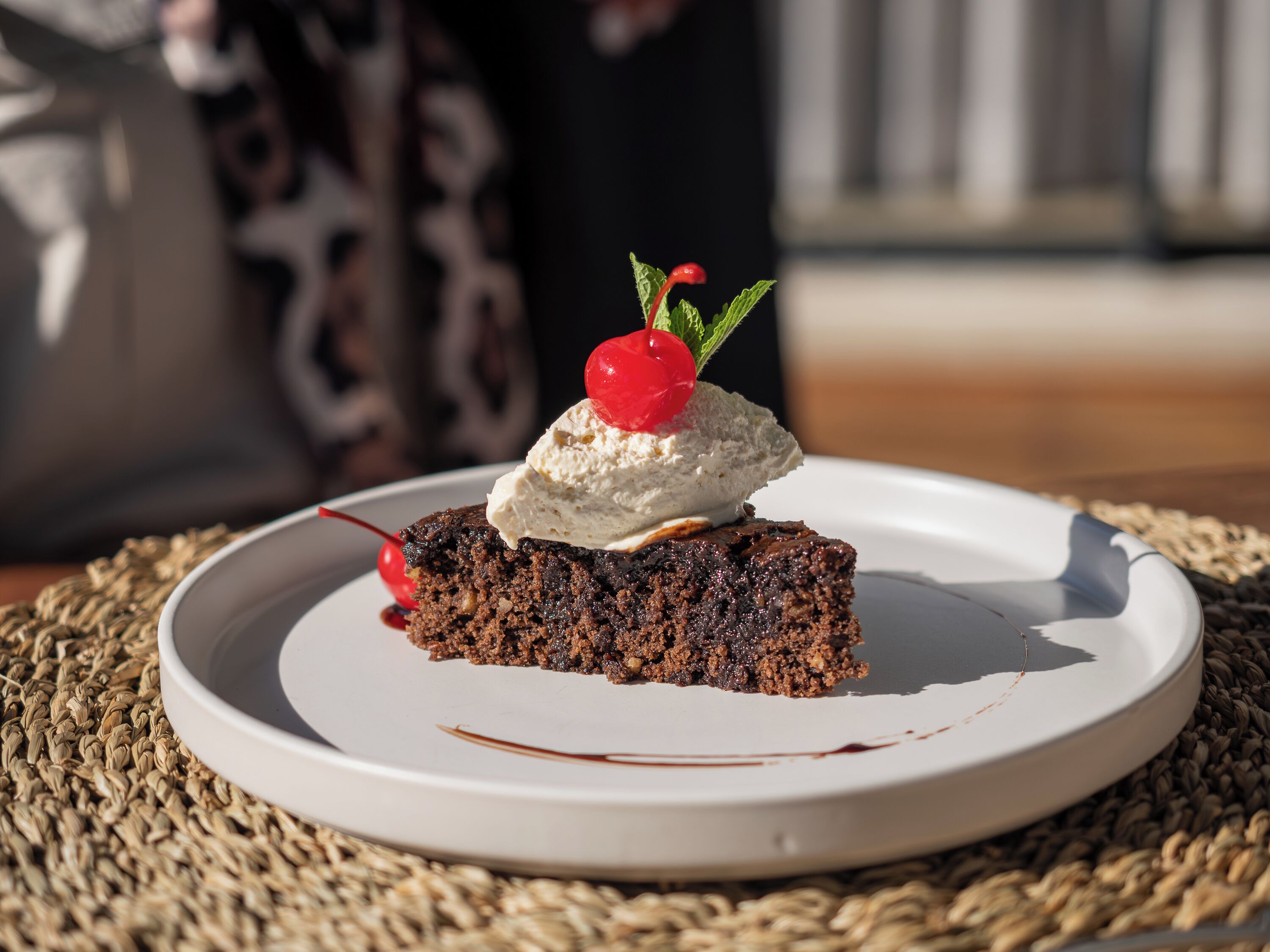 A slice of cake with whipped cream and a cherry on a white plate.