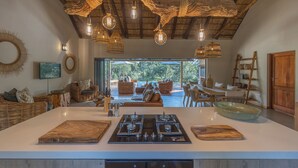 Uma cozinha ampla com uma ilha grande, eletrodomésticos modernos e teto rústico.