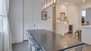 A modern kitchen with a dark countertop, white cabinets, and a hanging light fixture.