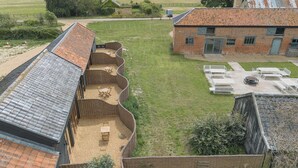 A courtyard with a brick building, a covered seating area, and a grassy lawn.