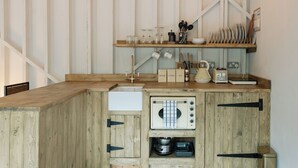 A compact kitchen with wooden cabinetry, a built-in toaster, and a coffee maker.
