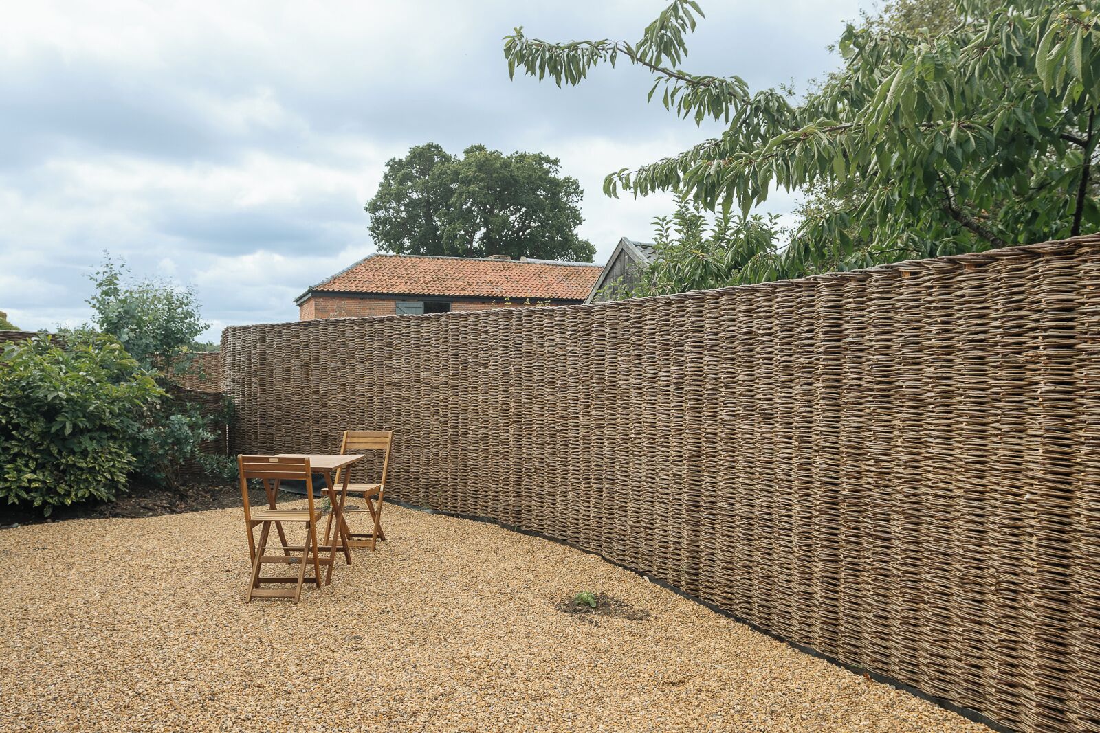 A patio area with a wicker fence, a table, and chairs.