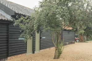 Traditional building with a tiled roof, featuring two entrance doors and a small tree.