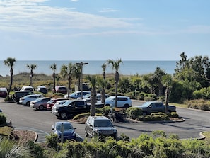 A parking lot with various cars and a view of the ocean.