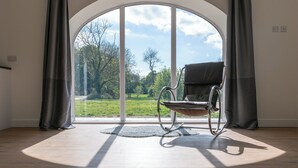 A room with a large arched window, a black leather chair, and a wooden floor. - Long Range 1, Henham Park Nr Southwold (Beccles)