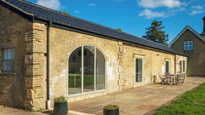 A brick building with large glass windows, a tiled roof, and a patio area with outdoor seating. - Long Range 1, Henham Park Nr Southwold (Beccles)