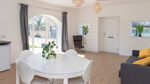 A modern living room with a white dining table, grey sofa, and a large window with curtains. - Long Range 1, Henham Park Nr Southwold (Beccles)