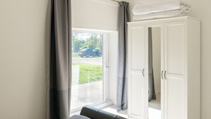 A bedroom with a bed, a wardrobe, and a sliding glass door leading to a parking area. - Long Range 1, Henham Park Nr Southwold (Beccles)