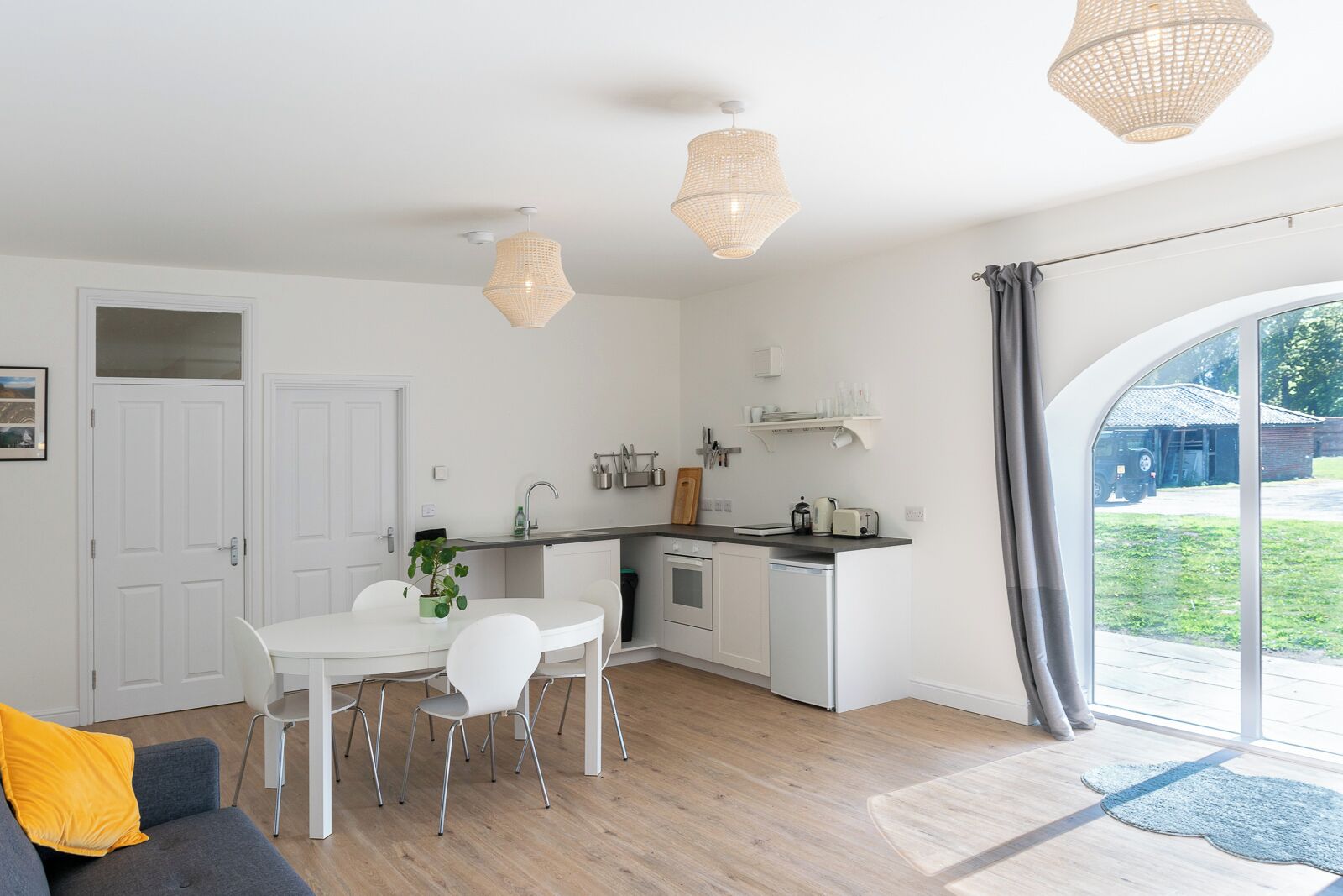 A modern kitchen with white cabinetry, a dining table with chairs, and pendant lights.