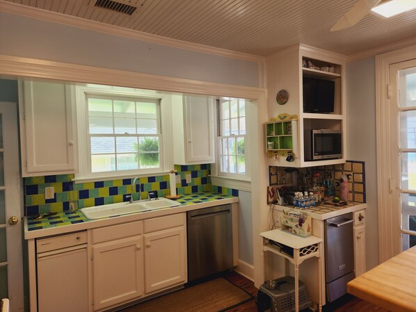 A kitchen with white cabinets, a stainless steel sink, and a microwave.