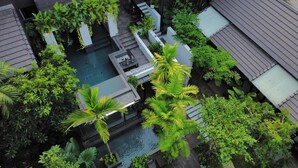 An aerial view of a residential area with a swimming pool surrounded by lush greenery and modern architecture.