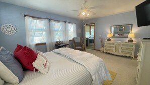 A bedroom with a bed, a chair, a dresser, a mirror, and a ceiling fan. - NEW LISTING: Breathtaking Waterfront Views w/ Private Dock  (Kill Devil Hills)