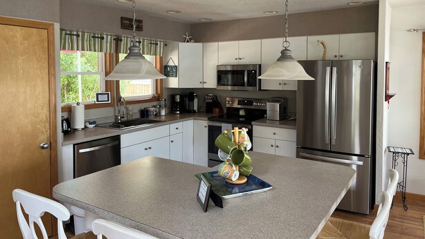 A modern kitchen with stainless steel appliances, a central island, and pendant lighting. - NEW LISTING: Breathtaking Waterfront Views w/ Private Dock  (Kill Devil Hills)