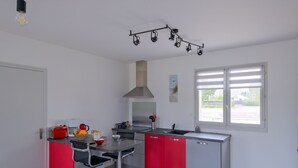 Una cocina moderna con una isla central, muebles rojos y un amplio ventanal que proporciona luz natural.